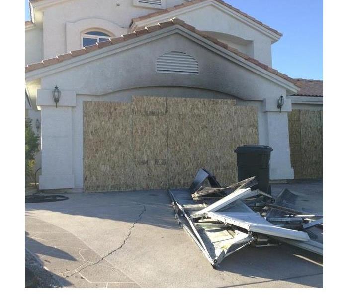 Garage fire boarded up. Garage door removed and temporarely placed in the driveway, black smoke visible on stucco.