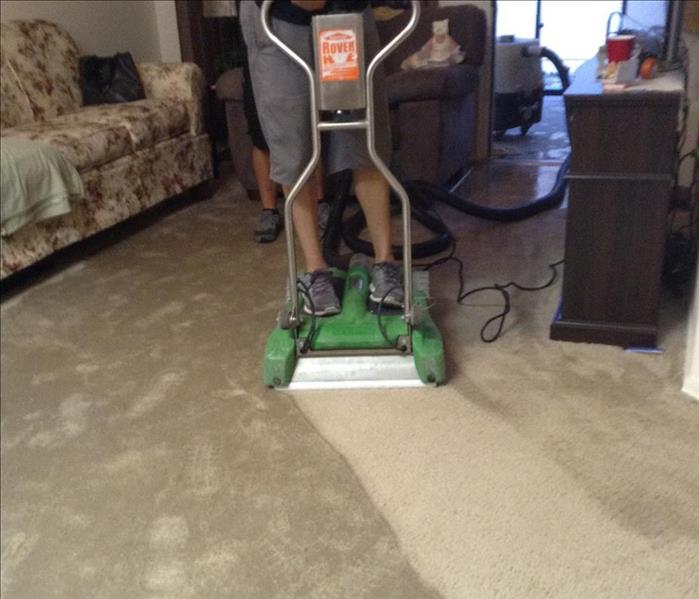 Aftermath of a water damage in a living room with furniture.  Water extraction with an electric scooter technician operated. 
