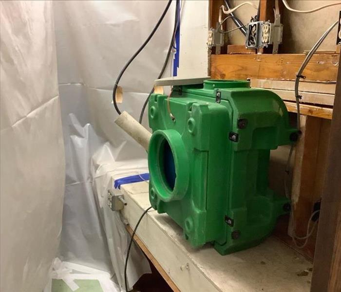 green air scrubber in place during a controlled demo inside a utility room of a commercial building.  