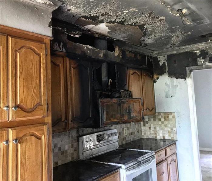 aftermath of a small kitchen fire with visible black smoke damages to the walls and cabinets. 